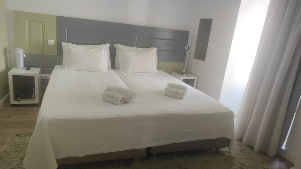 Quarto com duas camas feitas e toalhas dobradas depois da limpeza
